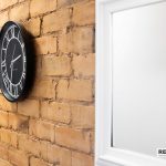 5f299541-da34-4034-9a03-7a350a32002djpg | RENT A ROOM | Professional House Shares in Warwickshire & West Midlands Round black clock with white Roman numerals mounted on an exposed brick wall beside a white door frame.