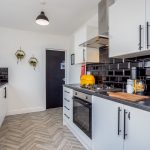 1f94b5c6-98fc-440a-b0c5-8c8c7e0cd486jpg | RENT A ROOM | Professional House Shares in Warwickshire & West Midlands Modern kitchen with white cabinets, glossy black tile backsplash, and stainless steel appliances.