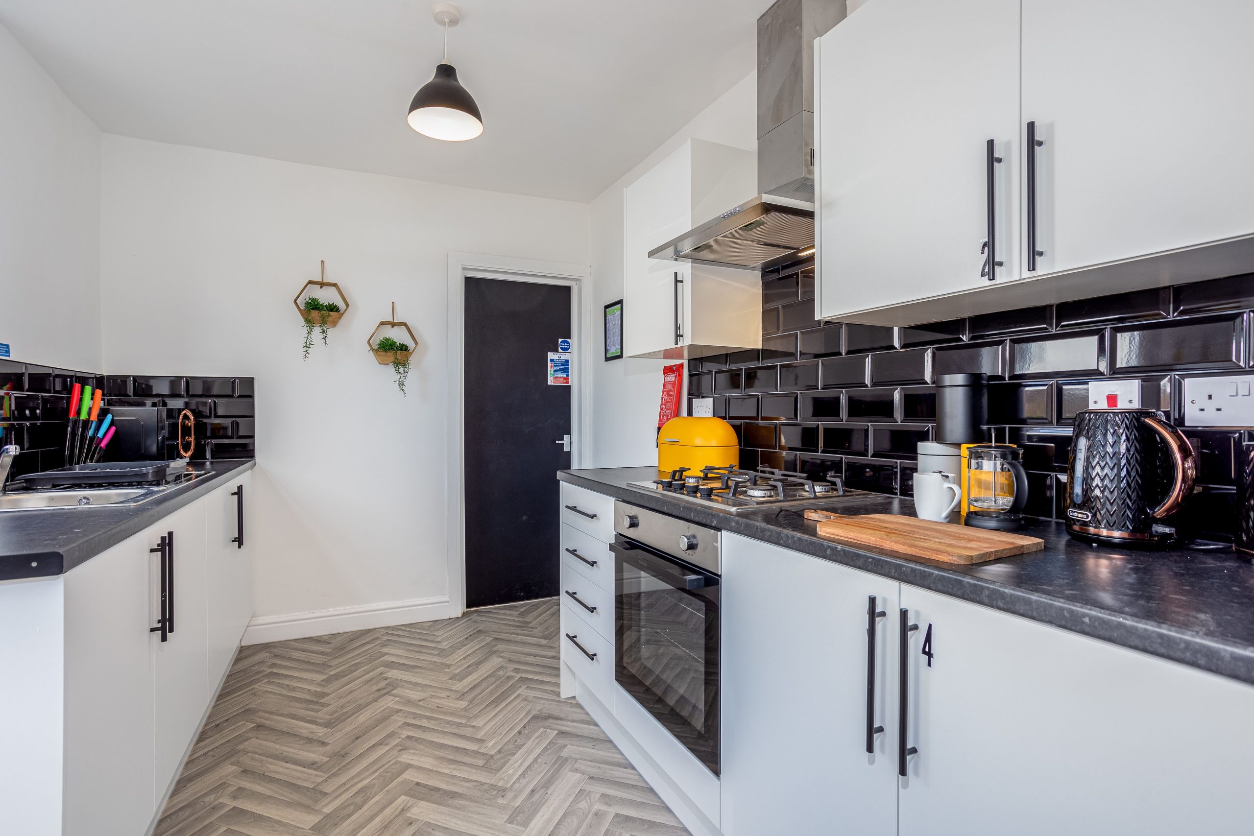 1f94b5c6-98fc-440a-b0c5-8c8c7e0cd486jpg | RENT A ROOM | Professional House Shares in Warwickshire & West Midlands Modern kitchen with white cabinets, glossy black tile backsplash, and stainless steel appliances.