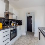 2190055d-a697-4468-9848-b443c23283fcjpg | RENT A ROOM | Professional House Shares in Warwickshire & West Midlands Bright, modern kitchen with white cabinets, a black tiled backsplash, and a yellow retro-style toaster on the counter.