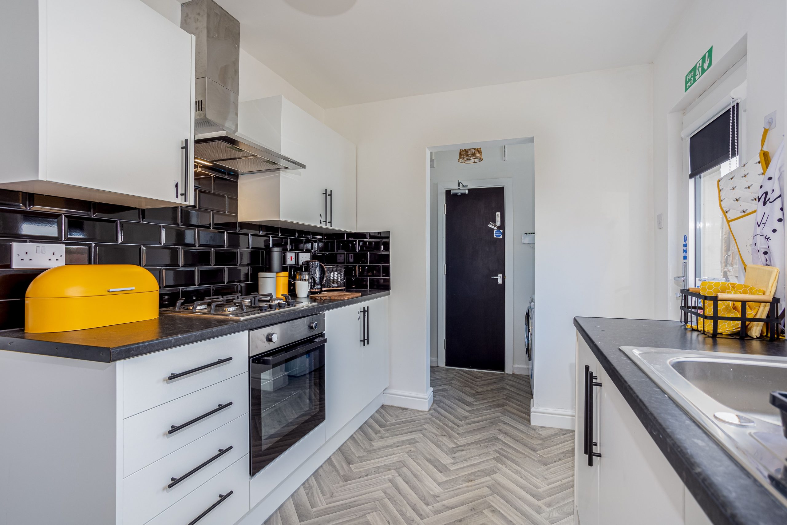 2190055d-a697-4468-9848-b443c23283fcjpg | RENT A ROOM | Professional House Shares in Warwickshire & West Midlands Bright, modern kitchen with white cabinets, a black tiled backsplash, and a yellow retro-style toaster on the counter.